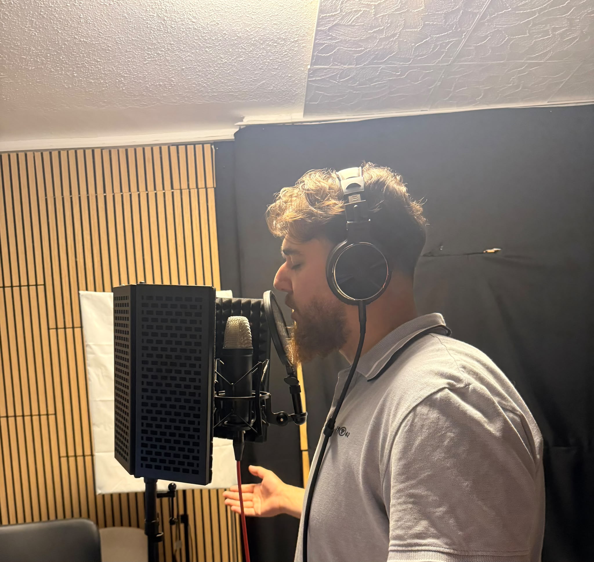Vocalist recording with headphones and studio microphone