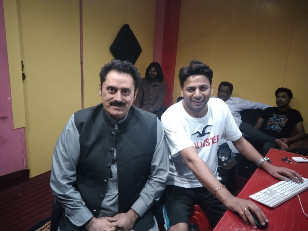 Two people seated at the Akhtar Sahb Studio control-room workstation